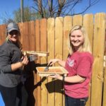 Mallory York and Baylie Borman, members of the new Rotaract club at William Woods University, stain the new gate.
